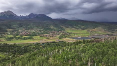 Abstieg-Auf-Einen-üppigen-Grünen-Wald-Aus-Espenbäumen-Mit-Zerklüfteten,-Stimmungsvollen-Bergen-Im-Hintergrund-In-Silverthorne,-Colorado,-Luftbild-Dolly-Drop