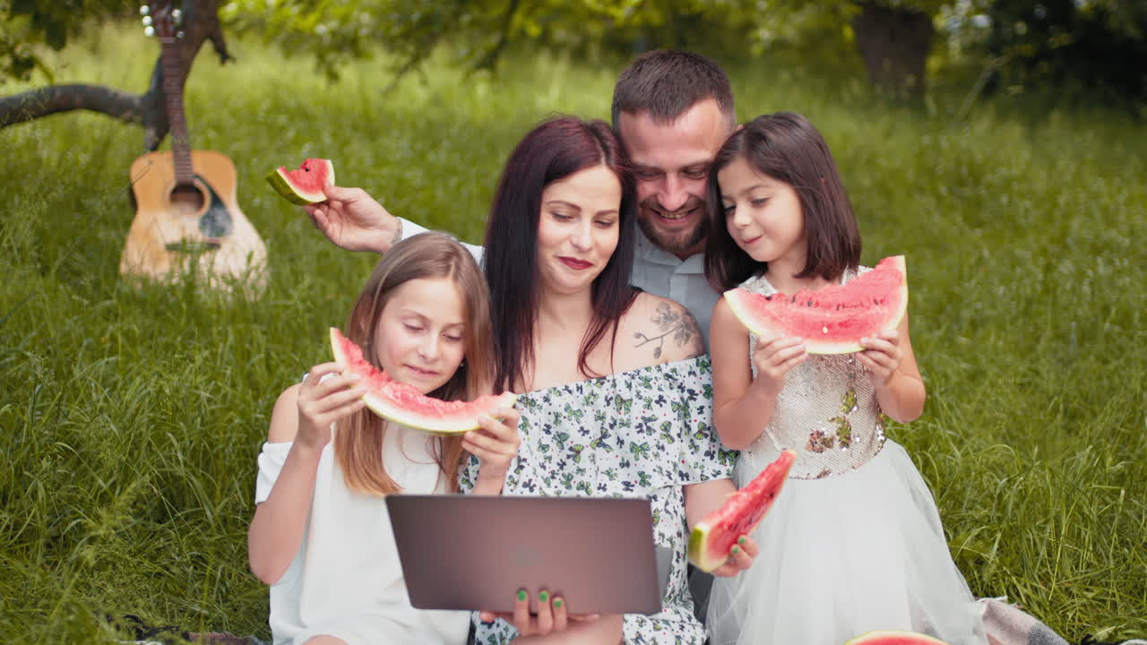 picnic familiar en el parque con sandía y portátil