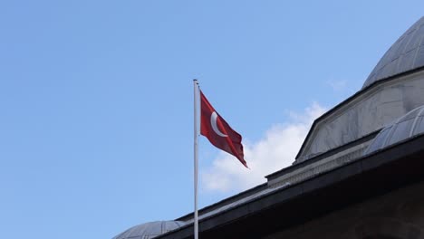 The-Turkish-flag-waves-proudly-against-a-clear-sky-backdrop,-symbolizing-national-pride-and-unity