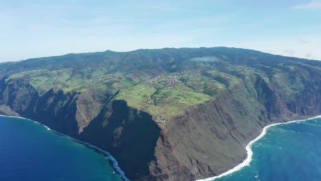 Volcanic-landscape-of-Madeira-with-tall-rocky-cliffs-surrounded-by-blue-water