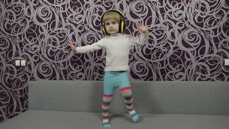 Un-Niño-Feliz-Saltando-Y-Bailando-En-El-Sofá-Y-Escuchando-Música-Con-Auriculares