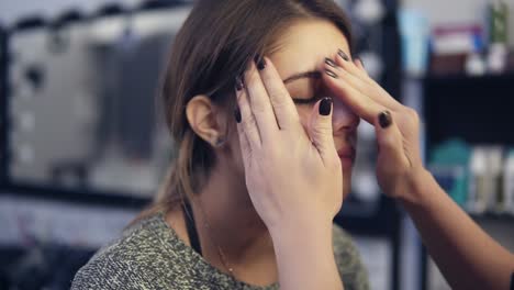 el artista de maquillaje aplica crema facial en el rostro de una chica joven usando sus manos. base para el maquillaje perfecto. disparo en cámara lenta