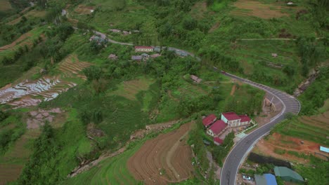 Following-the-main-road-with-surrounding-house-estates-on-aerial-view,-Sapa,-Vietnam