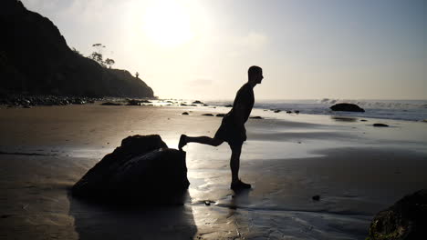 Un-Hombre-Musculoso-Fuerte-Haciendo-Estocadas-En-Las-Piernas-Para-Un-Entrenamiento-De-Fitness-Matutino-Al-Amanecer-En-Una-Playa-En-Santa-Barbara,-California