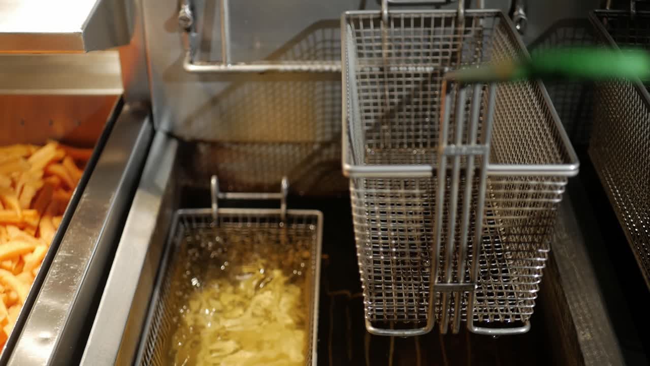 Kok lægger pommes frites og søde kartofler i frituregryde