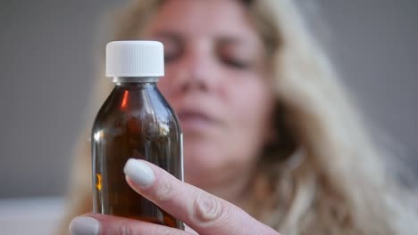 a woman reads the label of a cough syrup bottle