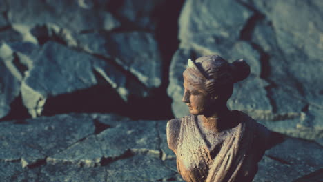 ancient statue of woman on rocky stones