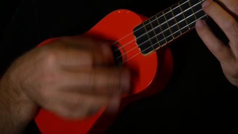 musician is playing some chords on an orange ukulele