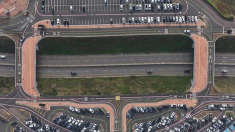 cars driving between tightly packed parking spaces on either side of the highway.