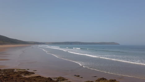 panorámica de izquierda a derecha de olas rompiendo contra una hermosa playa de arena en cámara lenta