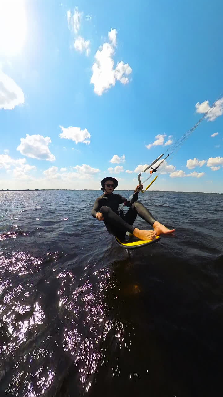 Kiteboarder Sitting On Hydrofoil Board While Gripping Control Bar Of Kite. vertical shot