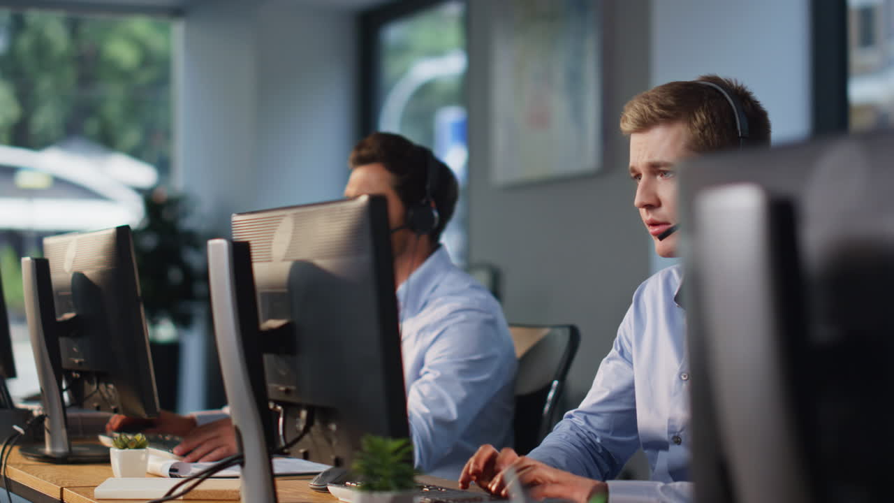 Contact center team working at computers talking headset in office space closeup