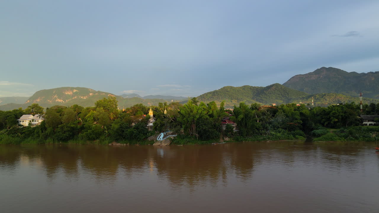 los últimos rayos de sol golpearon las orillas del mekong y las montañas más allá en luang prabang.