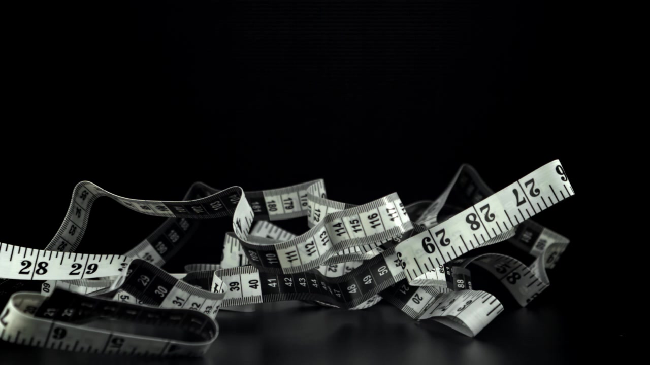Slow Motion of a Measuring Tape Dropping onto Black Background