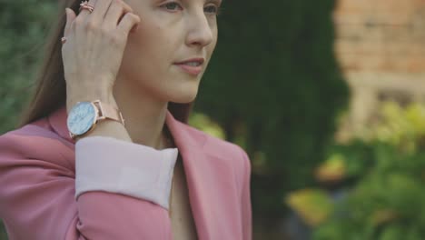 rack focus of good-looking woman in trendy light pink blazer walking outdoors - slow motion