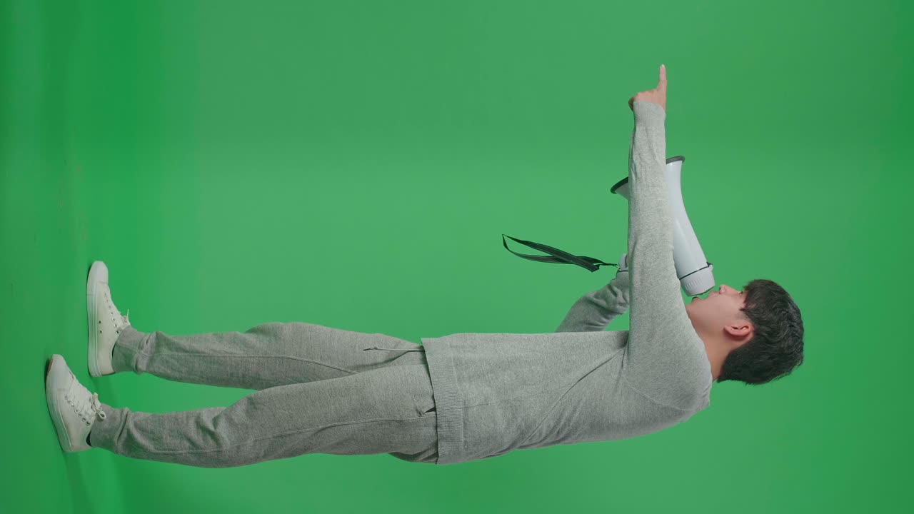 Full Body Of Side View Of An Asian Man Shouting On Megaphone In The Green Screen Studio
