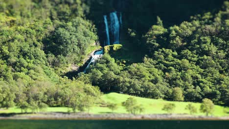 Imágenes-Con-Efecto-De-Cambio-De-Inclinación-Que-Muestran-Una-Cascada-Que-Fluye-A-Través-Del-Bosque-Verde-Sobre-El-Fiordo-De-Naeroy