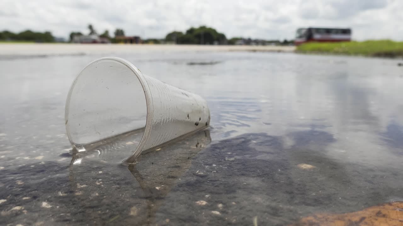 vaso de plástico arrojado a un charco de agua, contaminación