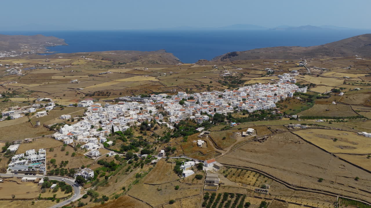 Kythnos Chora seaside settlement on Kythnos island on hilly terrain in afternoon, Cyclades, Drone shot, Panoramic view