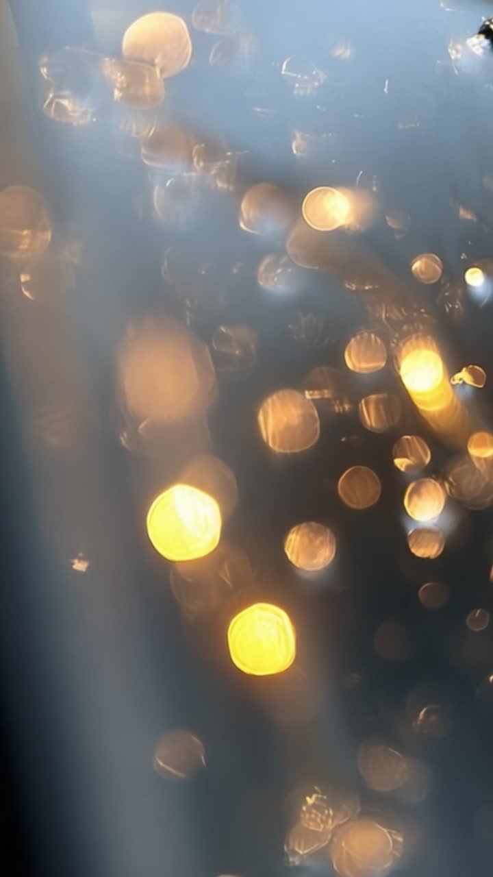 Captivating View of Glimmering Bokeh Lights Through a Window, Showcasing Beautiful Amber and Golden Reflections Merging with Soft Blurred Background