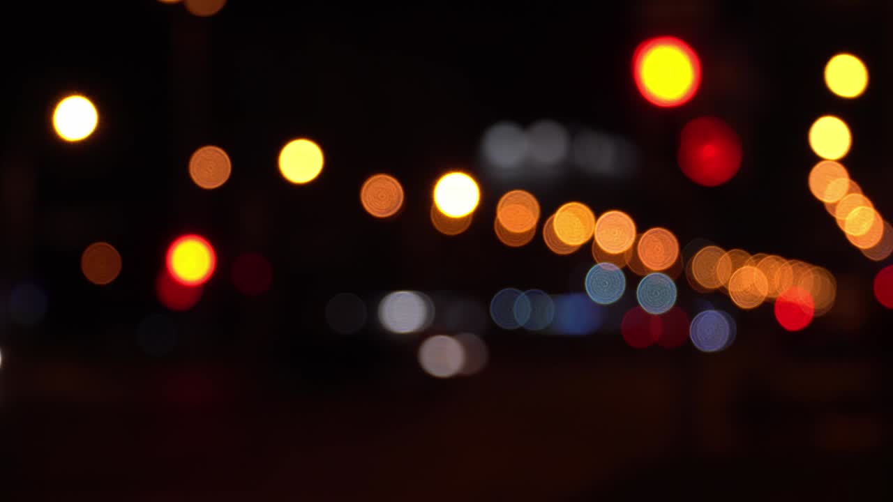 el colorido bokeh redondo brilla de las luces de los coches en el atasco de tráfico en la calle de la ciudad. hermoso bokeh brillante en el fondo oscuro borroso por la noche. concepto abstracto. refleja el estilo de vida solitario de la capital.