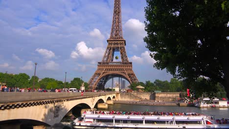 los barcos pasan por el río sena junto a la torre eiffel de parís