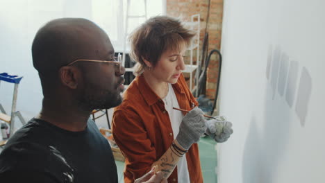 couple trying paint on wall and discussing color during home renovation
