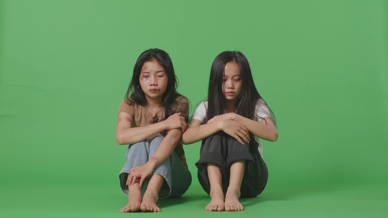 폭력의 희생자였던 젊은 아시아 여성들의 몸이 가득 차 있고, 몸에 이 있었고, 무을 고 앉아서 녹색 스크린 배경 스튜디오에 앉아 울고 있었다.