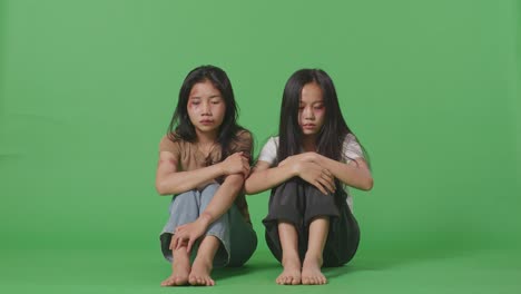 cuerpo lleno de jóvenes mujeres asiáticas víctimas de violencia con moretones en los cuerpos se sienta abrazando sus rodillas llorando mientras está sentada en la pantalla verde estudio de fondo