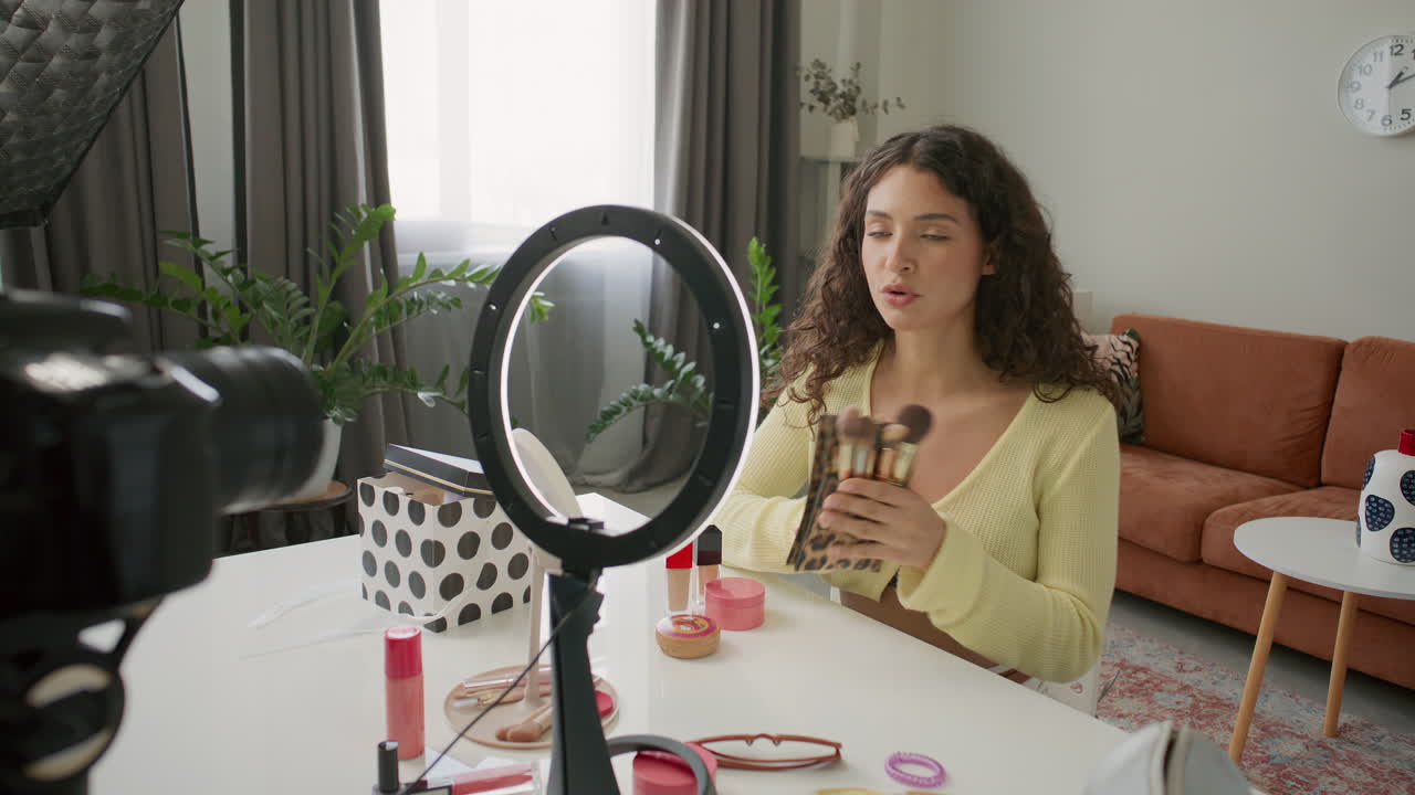 Female Beauty Blogger Presenting Makeup Brushes on Camera in Home Studio