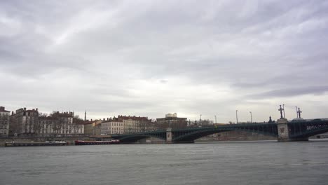 escena fluvial: barcos anclados a lo largo de las orillas del río ródano en lyon, con el viejo puente de hierro y la arquitectura clásica