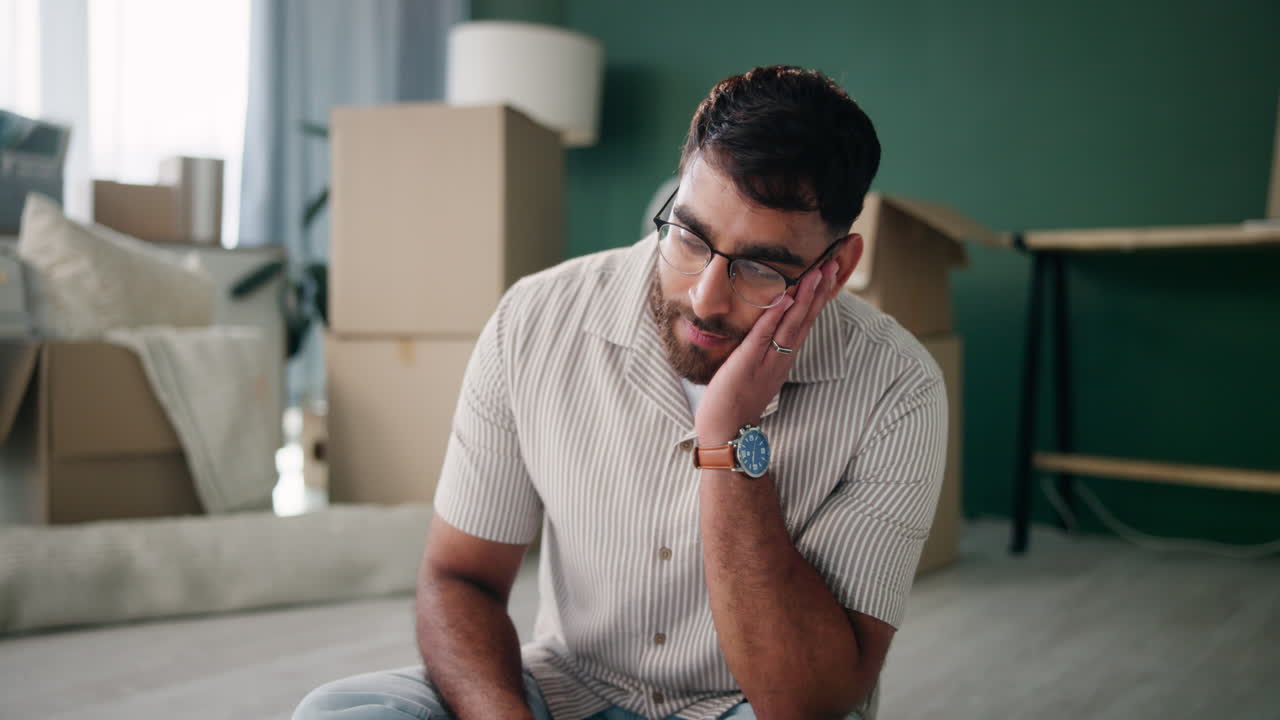 Man sitting on floor surrounded by moving boxes