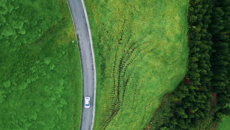 mountain serpentine road stretching greenery aerial top view. cars riding hills