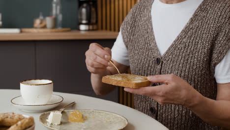 person spreading jam on toast at breakfast