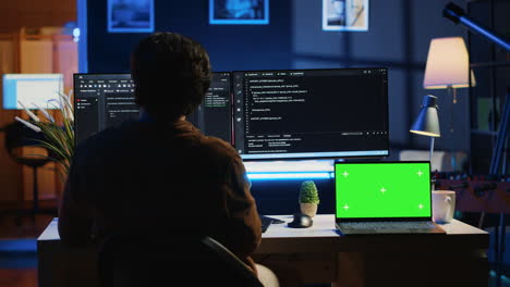 Programmer coding on computer next to isolated screen laptop in home office