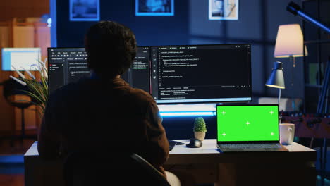 programmer coding on computer next to isolated screen laptop in home office