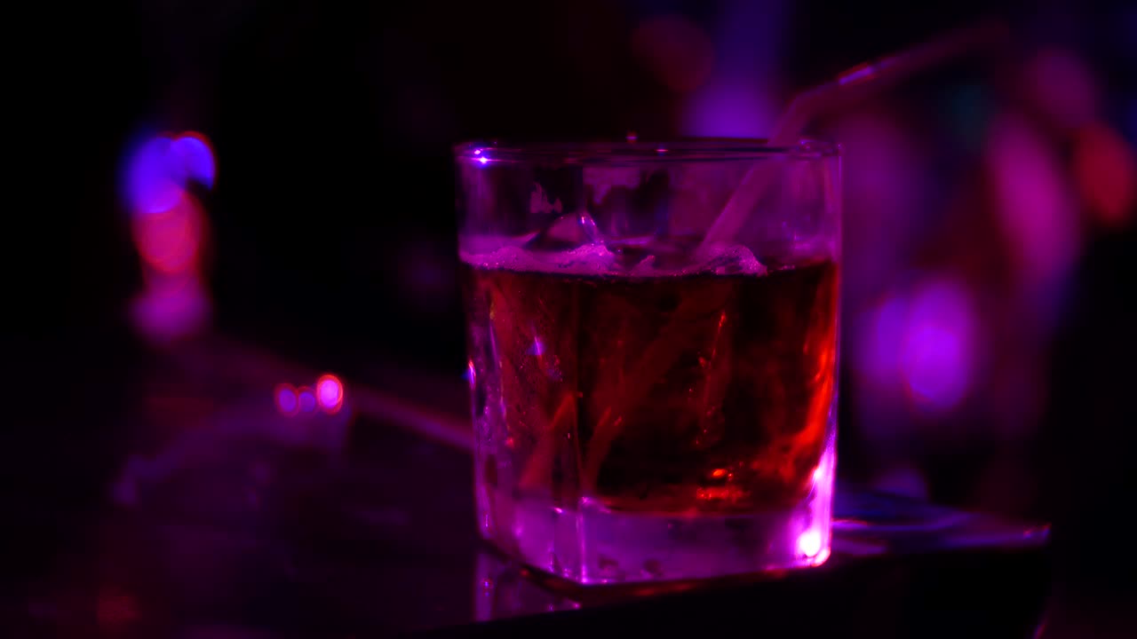 primo piano di un cocktail alcolico in bicchiere sul bancone di un bar, in un nightclub. sfocamento dello sfondo, 4k