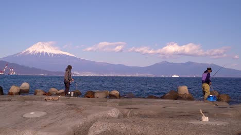 fishermen in japan fishing from stone pier with mt