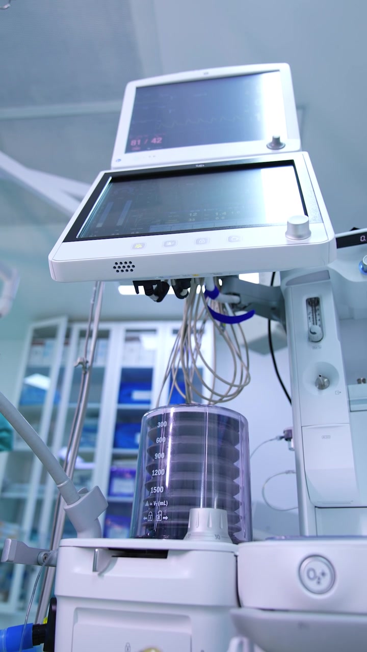 La bomba de la máquina de ventilación pulmonar bombea aire al paciente. Los signos vitales se muestran en los monitores del equipo. Vista en ángulo bajo. Video vertical.