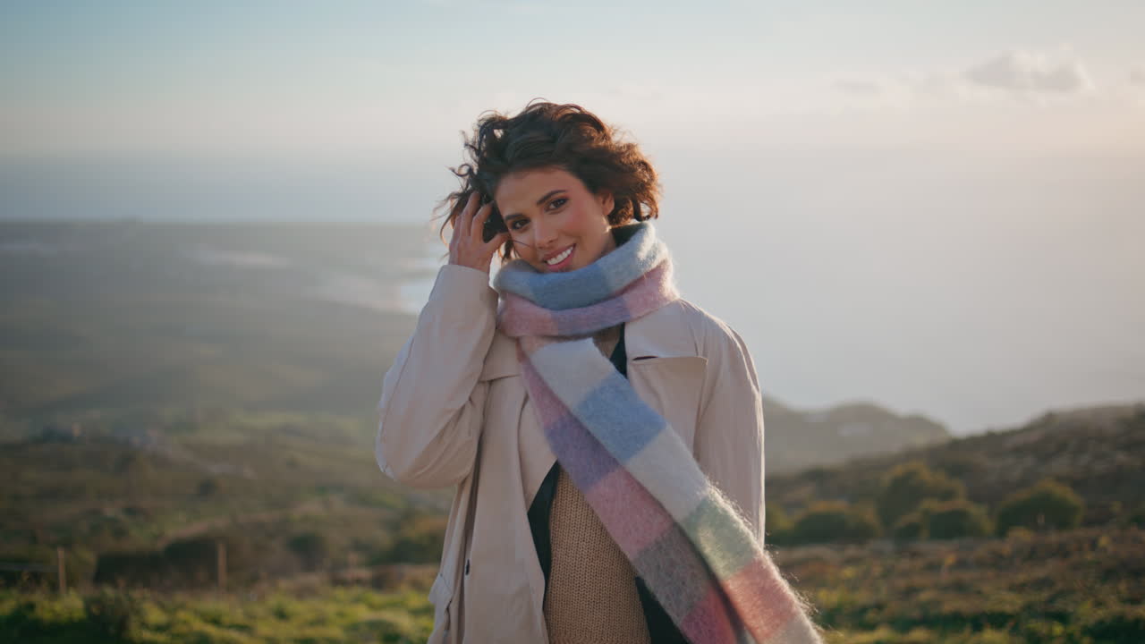 우아한 여행자가 서있는 풍경적인 해안 황혼은 시원한 바람에 의해 근접으로 불어.