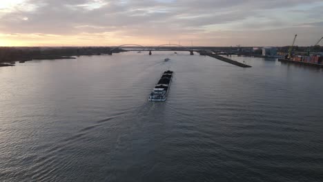 vista aérea del buque cisterna de carga navegando a lo largo del río durante la puesta de sol