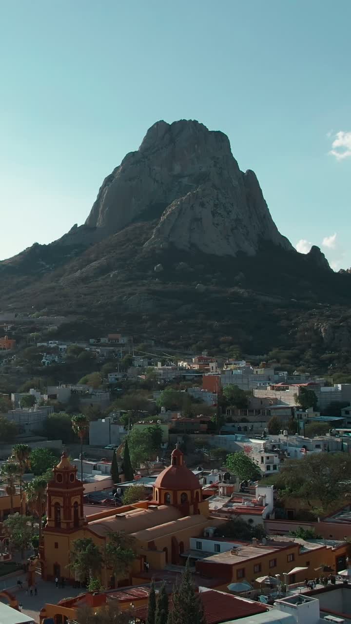 Ripresa aerea verticale del monolito roccioso Peña de Bernal con Bernal Pueblo Magico nella valle e il tempio di San Sebastian.