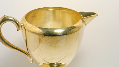 close up single silver-gold jug rotating in white background with dead space