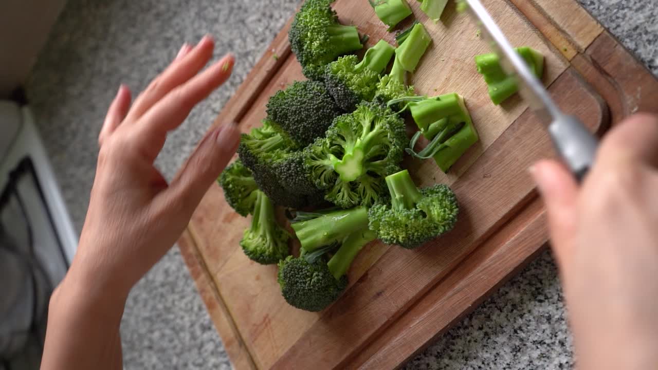 Vertical Shot Of Person Chopping Fresh Green Broccoli In Wooden Board