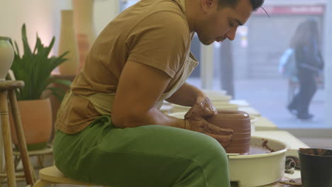 Alfarero-Masculino-Creativo-Sentado-Moldeando-Y-Trabajando-Cerámica-De-Arcilla-En-El-Plato-Giratorio-En-El-Taller-De-Estudio