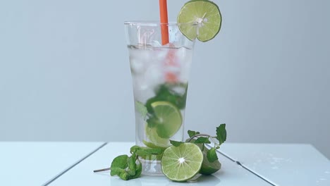 person-puts-lime-slice-on-glass-edge-on-white-table