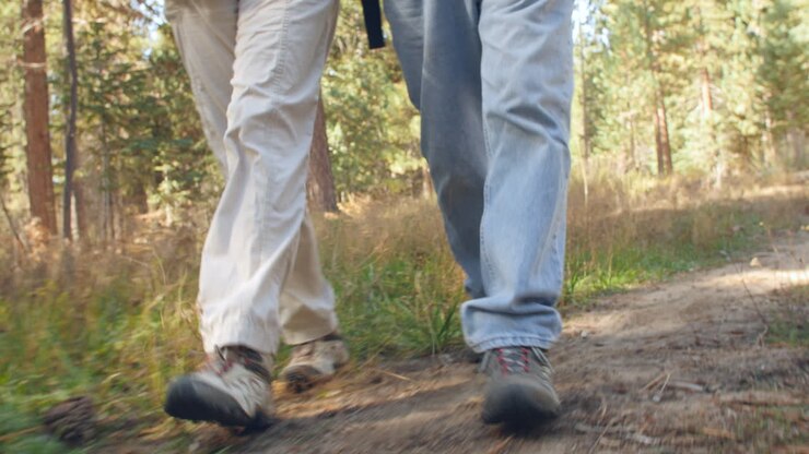 A man and a woman walking on forest trail, close up of legs