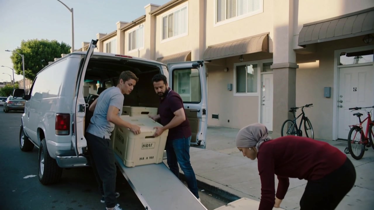 Unloading small crew sliding and lifting crates after rear doors opening by van ramp, moving boxes