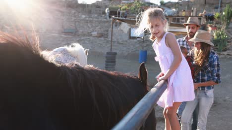 happy family having fun cuddling horses at farm ranch