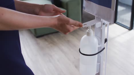 businesswoman using sanitizer to disinfect hands as he enters the workplace